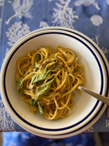 Plate of pasta with fork on blue tablecloth