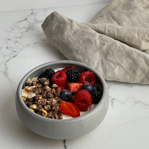 Bowl with yogurt, granola and berries with kitchen towel