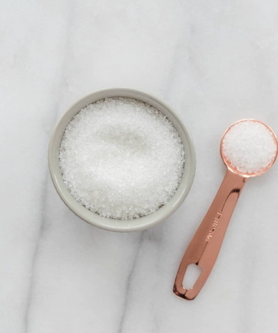Bowl with white sugar, pink teaspoon with white sugar