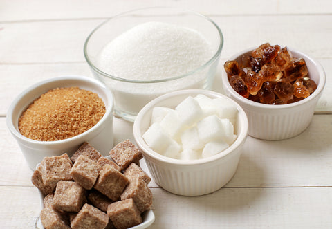Diversi tipi di zucchero su ciotole: zucchero bianco, di canna
