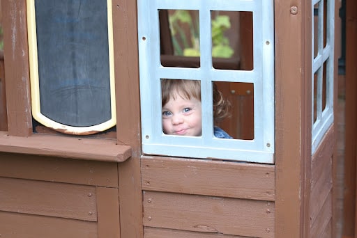 A child looks out of the window of their Amish-made playhouse.