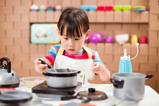 A young girl playing with a toy kitchen playset, demonstrating creativity in children.