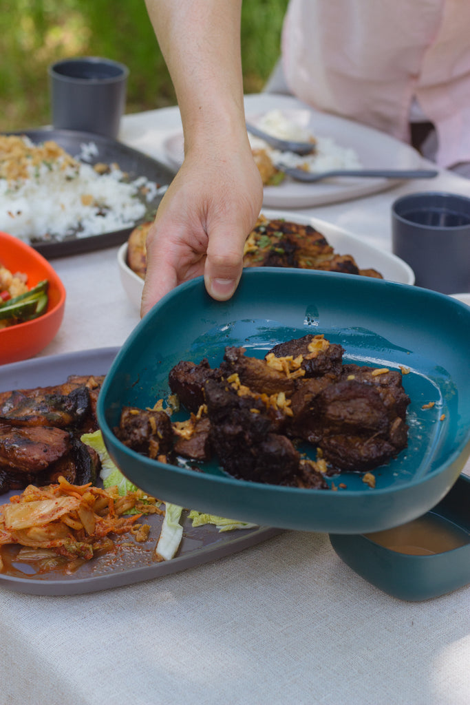 Bjorn holding an EKOBO Gusto Pasta Plate Bowl in Blue Abyss with chicken and pork adobo 