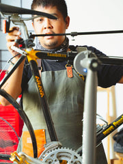 Eugene, our Head Technician, works on a bike while wearing a Gouache Bennet Apron.