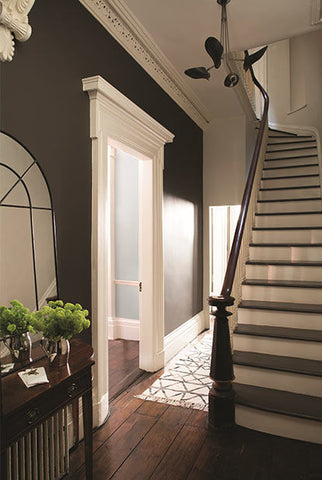 hallway with hardwood flooring and a doorway, leading to a staircase