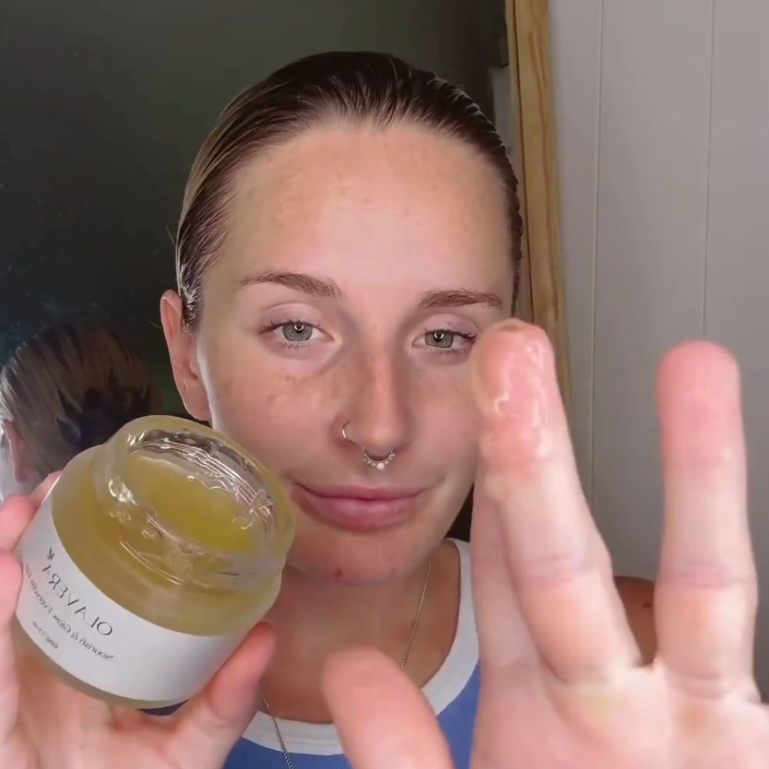 Person demonstrating a skincare product with a focus on their fingers and the product jar.