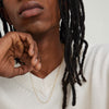 Man with dreadlocks wearing a white sweater, showcasing a gold Barrel Link Chain Necklace, highlighting its intricate design and fashionable appeal.