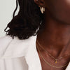 Close-up of a woman wearing a handcrafted 14k gold Birthstone Charm necklace, highlighting the elegant gemstone pendant on her neck.