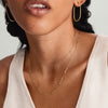 Woman wearing Boyfriend Bold Chain Necklace and gold hoop earrings. Close-up highlights the necklace's raw, bold design, complementing her white shirt.