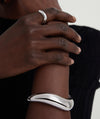 Person wearing the Dôme Figure Cuff, a handcrafted sterling silver bracelet, displayed prominently on the wrist.