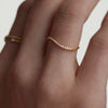 Close-up of a hand wearing the Figure Pavé Diamond Slim Stacker Ring, showcasing its 14k gold band with pavé diamonds.