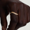 Close-up of a hand wearing the Dôme Figure Diamond Dipped Ring, featuring sleek curves, 14k gold, and pavé diamonds.