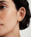 Close-up of a woman's ear showcasing Bezel Lab Grown Diamond Small Hoops in 14k solid gold featuring ethically produced lab-grown diamonds.