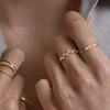 Person wearing a 14k gold Lab Grown Diamond Baguette Stacker Ring, showcasing a baguette diamond centerpiece, complemented by other gold jewelry pieces.