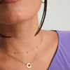 Woman wearing the Linked Pavé Diamond Pearl Necklace featuring two interlinked rings in 14k gold with responsibly sourced diamonds and mother of pearl.