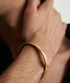 Close-up of a wrist adorned with the Bold Cuff Brushed Gold, showcasing its simple yet bold silhouette and handcrafted 14k yellow gold design.