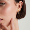 Close-up of a woman's ear wearing elegant pearl drop earrings.