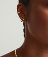 Close-up of a woman's ear adorned with Mini Lotus Diamond Studs, handcrafted in 14k gold with lotus-shaped, responsibly sourced diamonds.