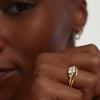 Close-up of a woman's hand wearing the Nesting Band, a gold ring, highlighting its elegant design and fit.