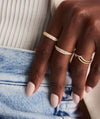 A hand adorned with the Wishbone Stacker Set Archive, featuring two gold rings, one with pavé diamonds, emphasizing a stylish ring stack.
