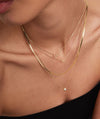 A woman wearing a 14k gold Zodiac Sign Necklace, featuring a delicate chain and a personalized letter charm.