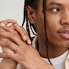 Man with braids displaying a 2mm Curve Band on his finger, highlighting the ring's lightweight and lasting design.