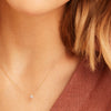 Close-up of a woman wearing the Pavé Diamond Round Necklace, showcasing 14k yellow gold with pavé diamonds set in rhodium white gold pen plating.