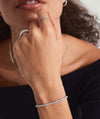 Close-up of a woman's hand wearing a Lab Grown Diamond Tennis Bracelet 2.5mm, showcasing its sparkle and intricate 14k solid gold setting.