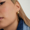 Close-up of a woman wearing Chunky Medium Hoops with a clicker closure, emphasizing the earrings' pillowy texture and secure fit.