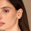 Close-up of a woman's ear adorned with a Single Diamonds Line Mini Hoop, a delicate 14k gold hoop set with diamonds.