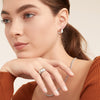 Woman wearing Dôme Hoops earrings, hand on chin, showcasing a classic, bold ring design. Ideal for pairing with daintier rings for a stylish stack.