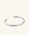 Slim Cuff: A silver bracelet with a simple silhouette, featuring a letter M charm, ideal for versatile styling.