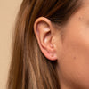 Close-up of a woman's ear wearing a Single Sphere Stud earring, showcasing its simplicity and versatility for solo or paired wear.