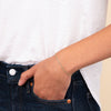 Person wearing the Curb Bracelet, a 14k gold chain, with their hand resting on a blue jeans pocket.