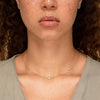 Close-up of a woman's neck wearing the Satellite Necklace, handcrafted in 18k gold vermeil with white sapphires, showcasing its delicate design and elegant style.