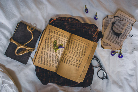 Burnt books, glasses, and ropes, on a bed