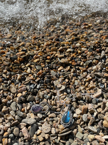 Blue labrodite sterling silver pendant and Lepidolite Sterling Silver pendant lying on the river stones at Bow Lake in Banff national park