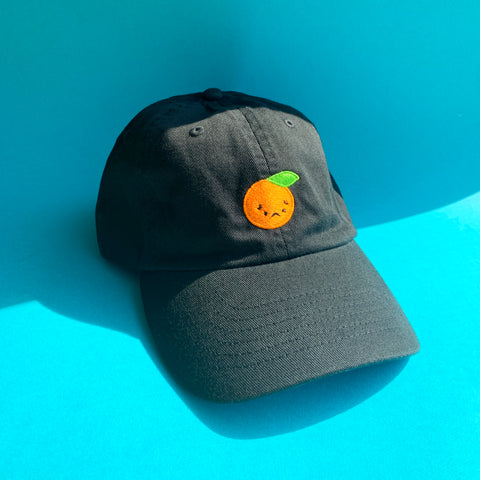 Black baseball cap with a frowning orange embroidered on the front