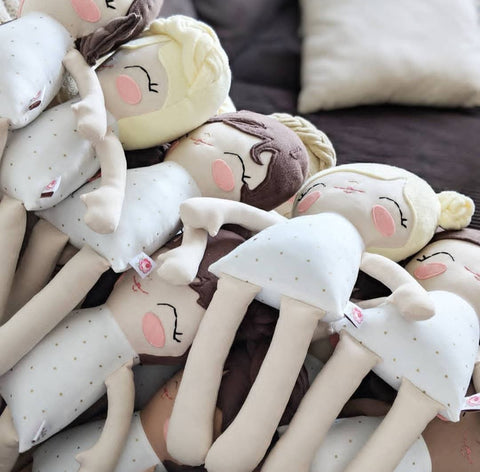 Pile of Pockets with Posies dolls of varying skin tones and hair colors laying on a couch. 