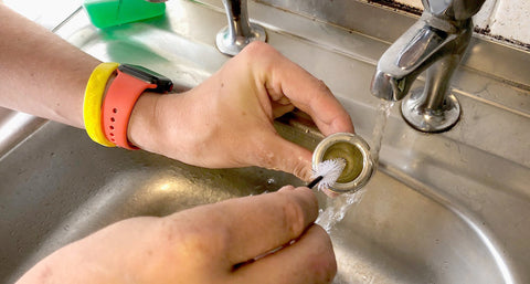 Cleaning a brass mouthpiece with brush and water.