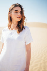 Woman posing in the desert in a white linen dress.