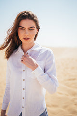 Woman standing in the Dubai desert in a white women's linen shirt.