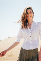 Woman wearing a white linen blouse and positing in the desert.