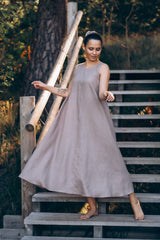 Woman wearing a brown linen dress standing on the stairs.