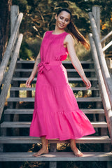 Femme vêtue d'une robe en lin rose debout dans les escaliers