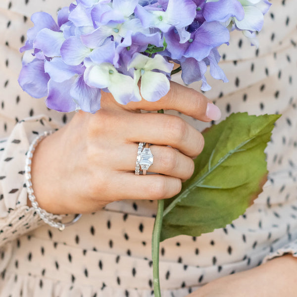 Emerald diamond ring with hand holding flowers