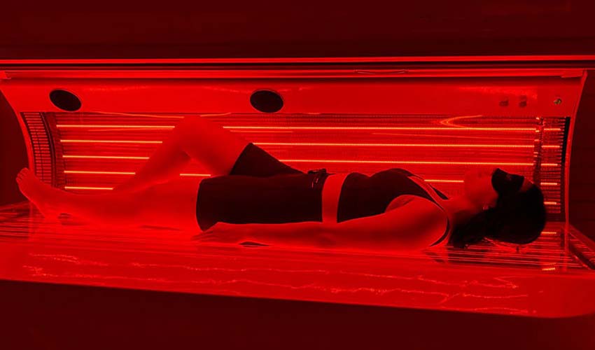 A woman receiving red light therapy in the spa center.