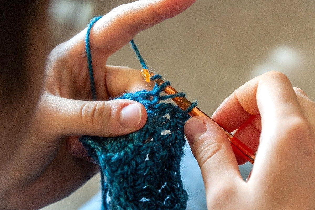 A close-up of a person's hands knitting something