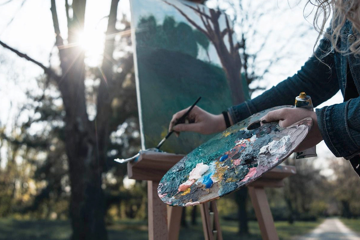 A painter painting outside at dawn, in what looks like a park