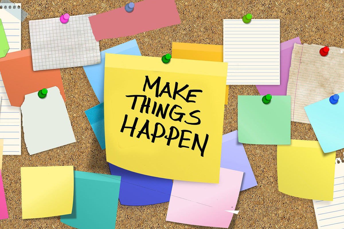 Post-it notes and scrap papers on a cork board, with the message "Make things happen" in the middle